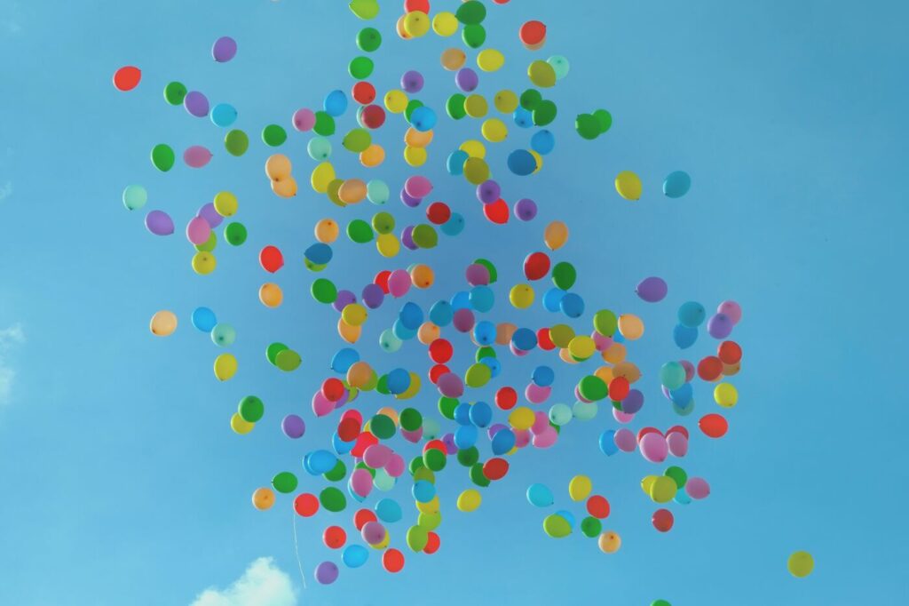 Luftballons in Regenbogenfarben fliegen in die Luft